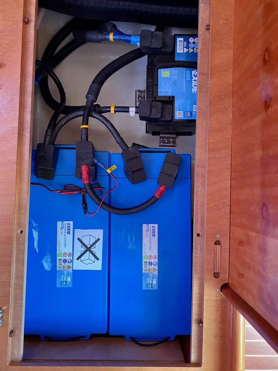Die neuen Batterien sind eingebaut. Das neue kleine Kabel an der linken Verbraucherbatterie dient der Temperaturmessung durch den Batteriemonitor (und dessen Spannungsversorgung). Auf dem Bild fehlt noch die obere Querstrebe, die die Batterien nach unten fixiert.
